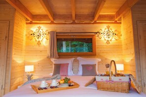 Um quarto de cabana de madeira aconchegante, com uma cama, uma janela e uma bandeja de café da manhã no criado-mudo.