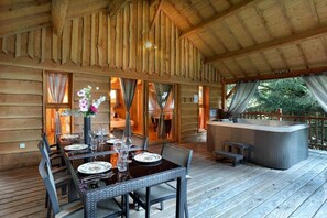 Une terrasse en bois avec une table à manger pour quatre personnes, un jacuzzi et une vue sur l’extérieur.