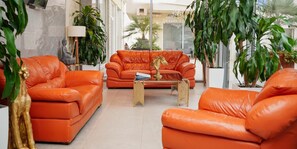 A living room with orange leather sofas, a coffee table, and a Buddha statue. - Edart Hotel (Durrës)