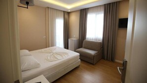 Una habitación de hotel con una cama, una silla, un televisor y una lámpara.