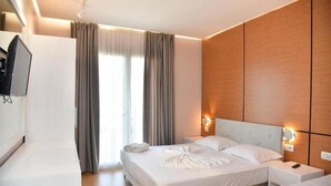 Una habitación de hotel con una cama grande, un televisor montado en la pared y una ventana con cortinas.
