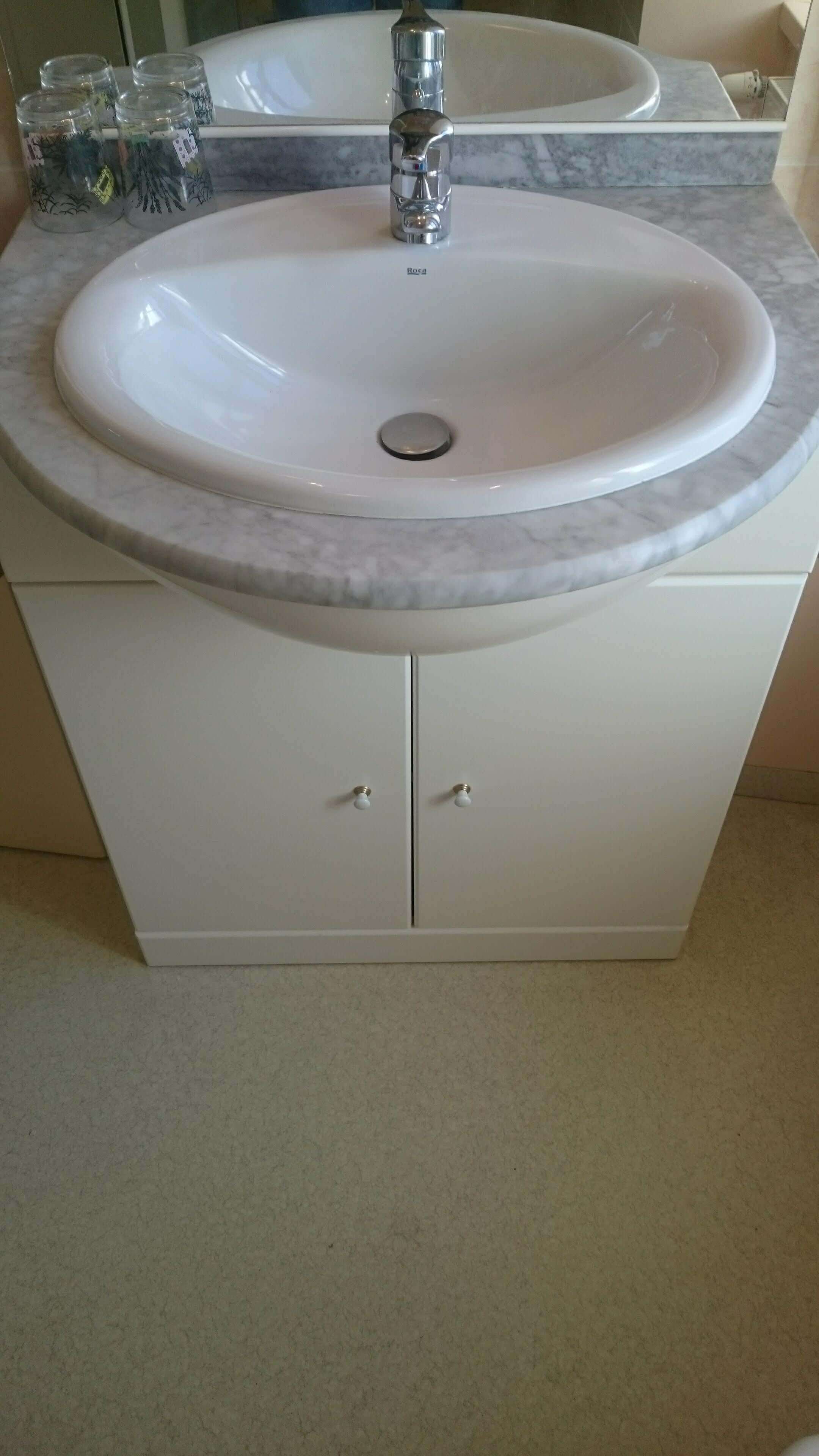 Une salle de bain avec un lavabo blanc, un miroir et un meuble avec deux tiroirs.