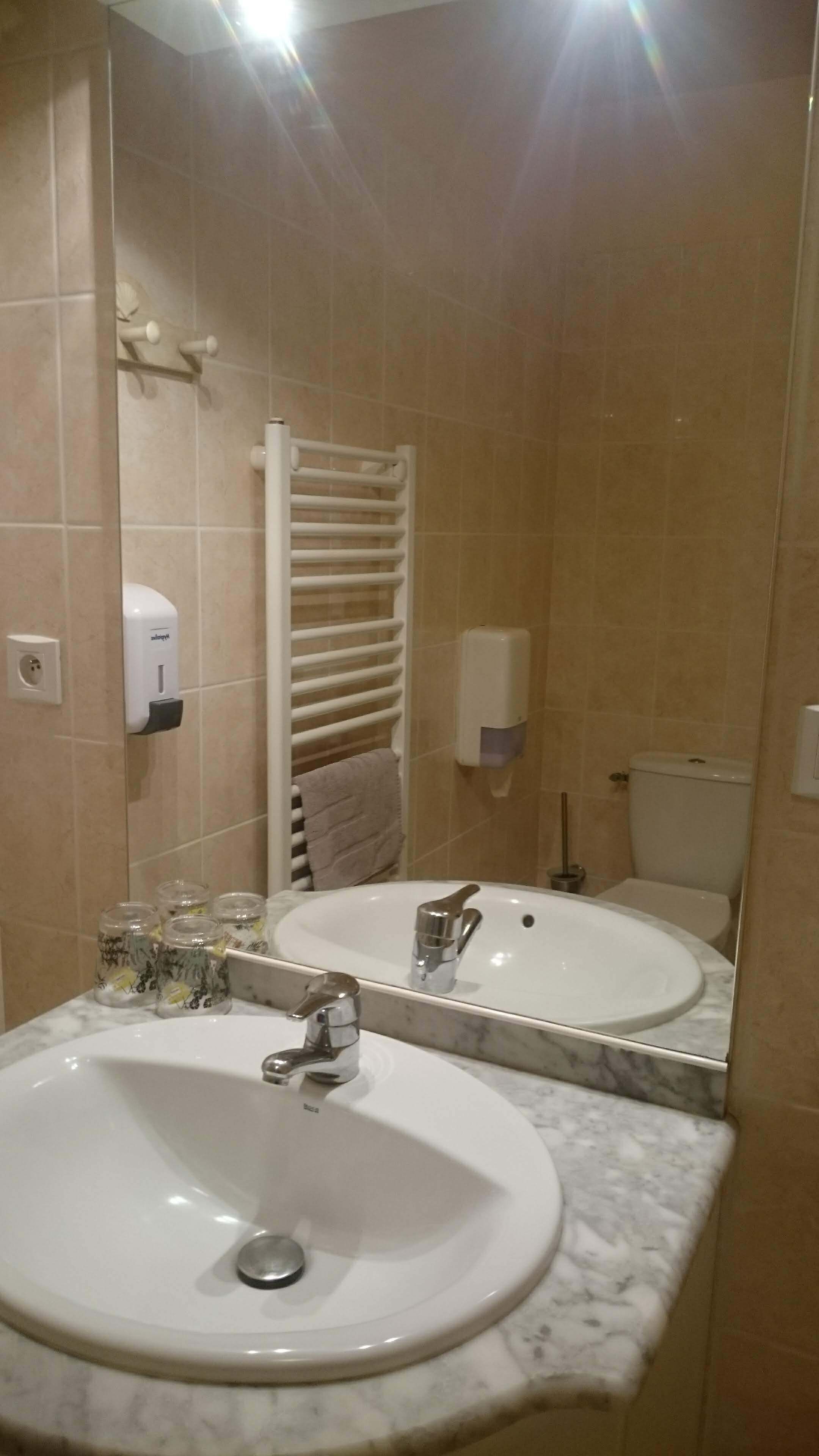 Een badkamer met twee wastafels, een handdoekhouder, een toilet en een spiegel.