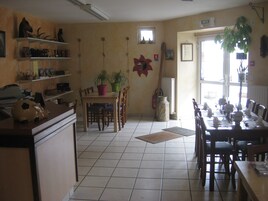 Un comedor con una mesa larga dispuesta para una comida, sillas, una planta en maceta y un extintor.