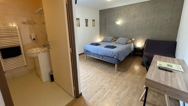 Une chambre d’hôtel avec un lit, une table de chevet et une petite table sur laquelle se trouve une télécommande.