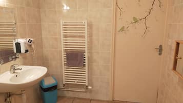 Ein Badezimmer mit Waschbecken, Spiegel, Handtuchhalter und einer Tür mit Zweig-Motiv.