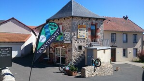 Un bâtiment en pierre avec une enseigne indiquant « AUBERGE L’ASTRASSADOU », proposant une cuisine traditionnelle et un bar.