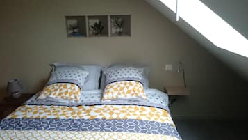 Une chambre à coucher avec un lit, une table de chevet, une lampe et une petite table sur laquelle est posée une plante.