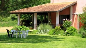 A house with a covered patio, a garden with various plants, and a table with chairs. - Agriturismo La Praduscella (Fivizzano)