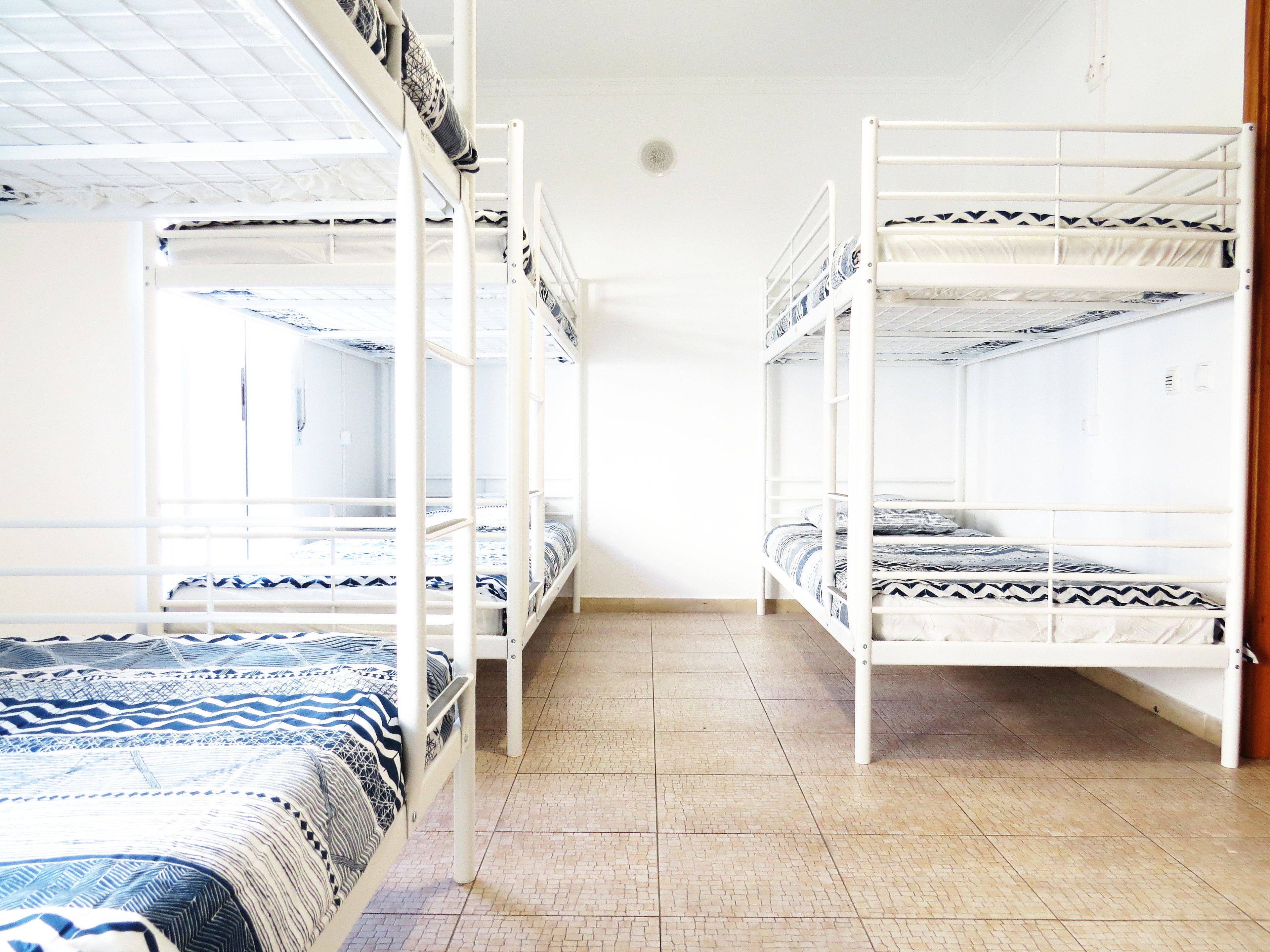 Un dormitorio con literas, suelo de baldosas y una ventana con persianas.