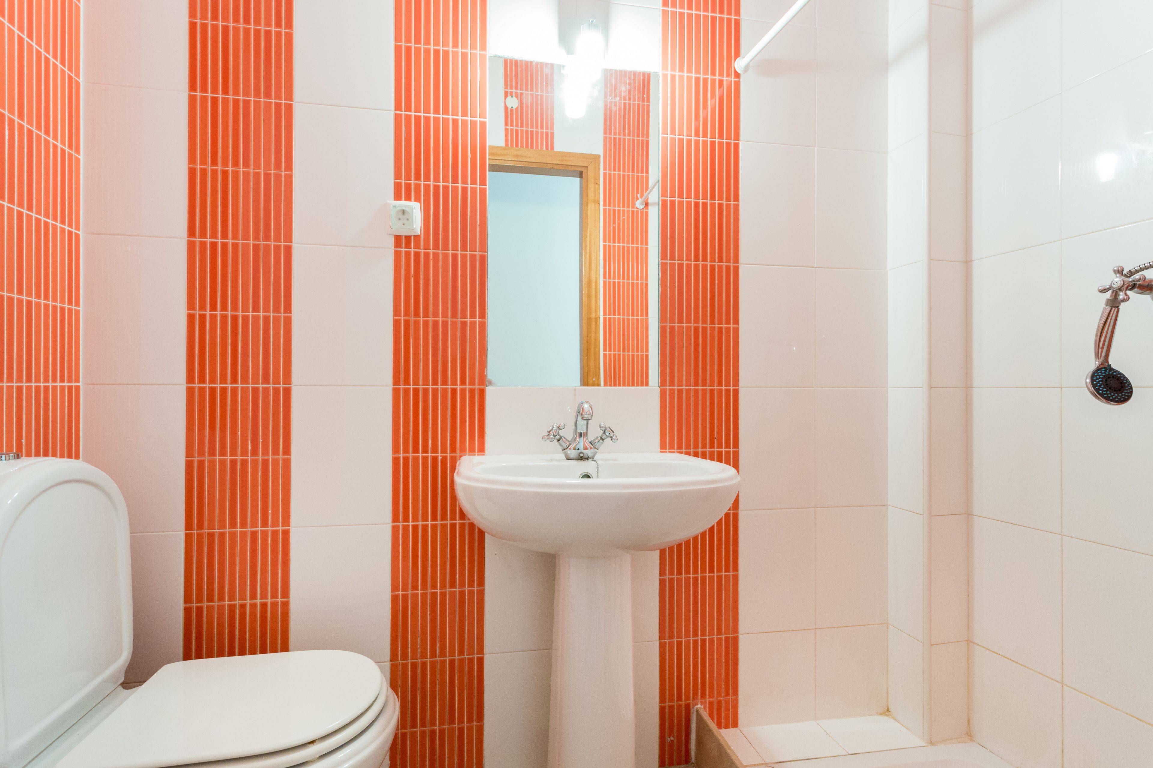 A bathroom with a white toilet, a white sink, and a shower area.