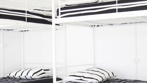 A bunk bed room with white walls and black and white striped bedding. - The 17 Hostel (Lagos)