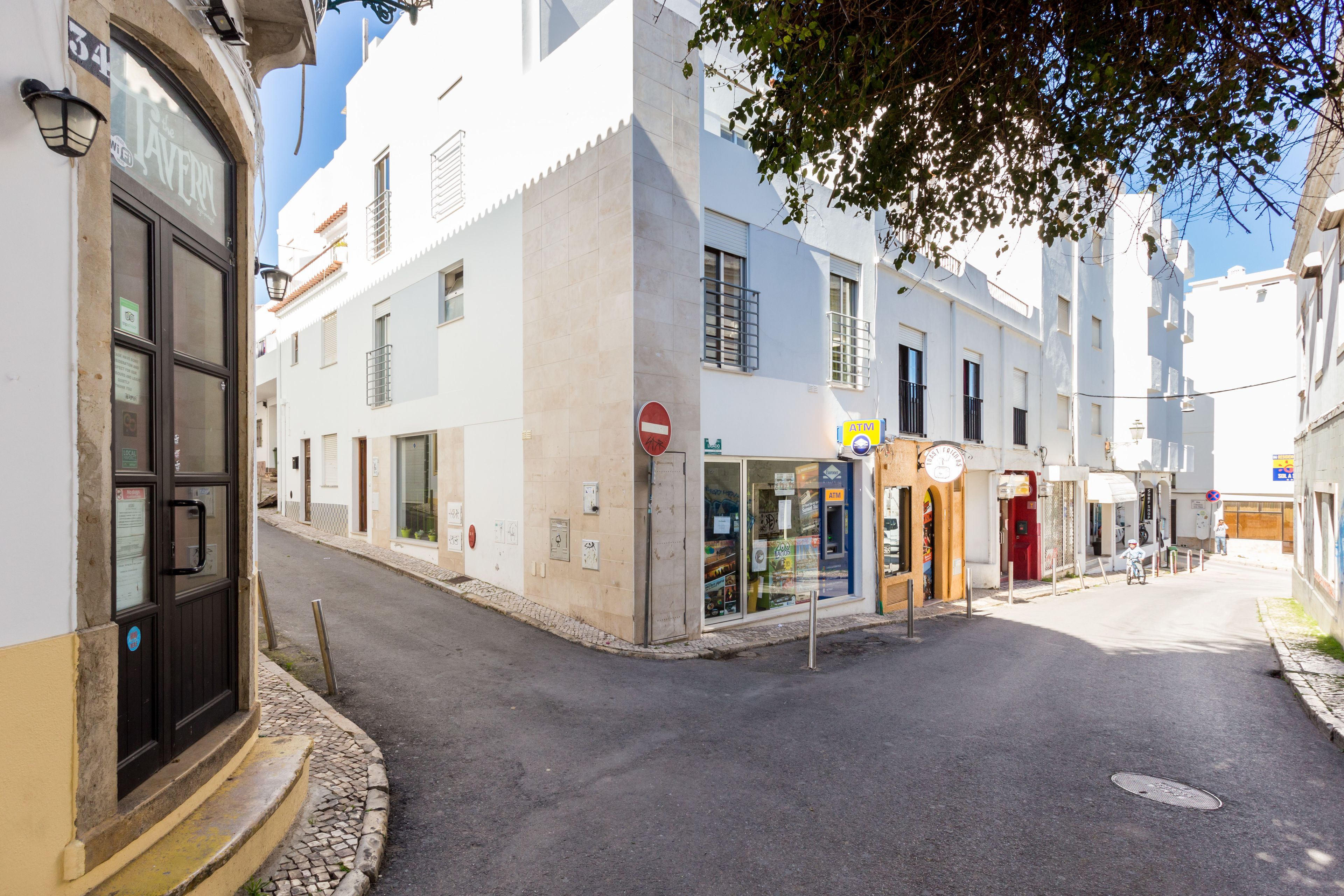 Une rue étroite, bordée de bâtiments des deux côtés, avec un panneau indiquant l’interdiction d’accès et un vélo garé sur le côté droit.