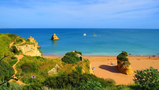 A coastal landscape with cliffs, a sandy beach, and a clear blue sea. - The 17 Hostel (Lagos)