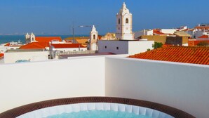 A hot tub on a rooftop with a view of a coastal town and a church tower. - The 17 Hostel (Lagos)