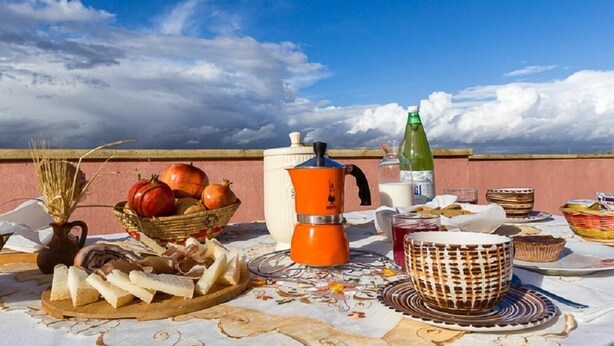 A table set outdoors with food items, a coffee maker, and a bottle of water. - B&B Su Connotu (Sestu)