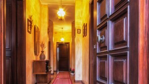 A hallway with a wooden door, a red rug, and a chandelier. - B&B Su Connotu (Sestu)