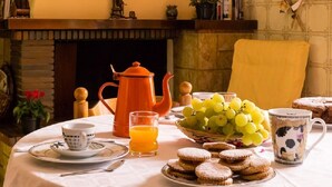 A breakfast setting with a table set for two, including a teapot, cups, a glass of orange juice, a bowl of grapes, and pastries. - B&B Su Connotu (Sestu)