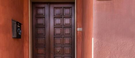 Une porte en bois à deux battants, avec un socle en pierre et une plaque indiquant le numéro de la chambre : 16.