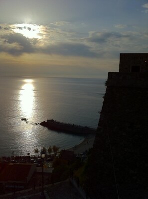 Vista costera con un muro de piedra y un muelle que se adentra en el agua.