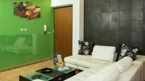 Un salón con una pared verde, un sofá blanco y una pared de acento con azulejos negros.