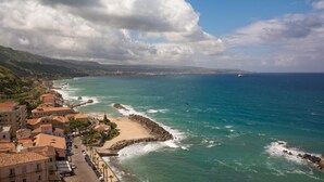 Un pueblo costero con edificios a lo largo del mar, un rompeolas rocoso y una vista despejada del océano.