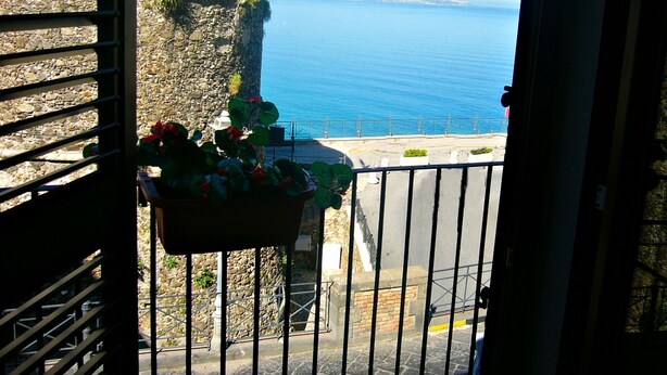 Un balcón con pared de piedra y vista al mar.