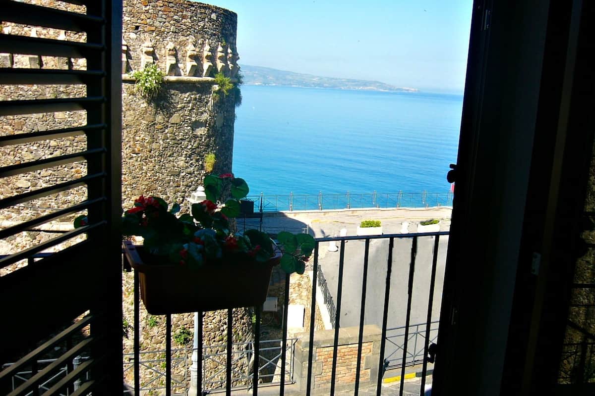 A balcony with a stone wall and a view of the sea.