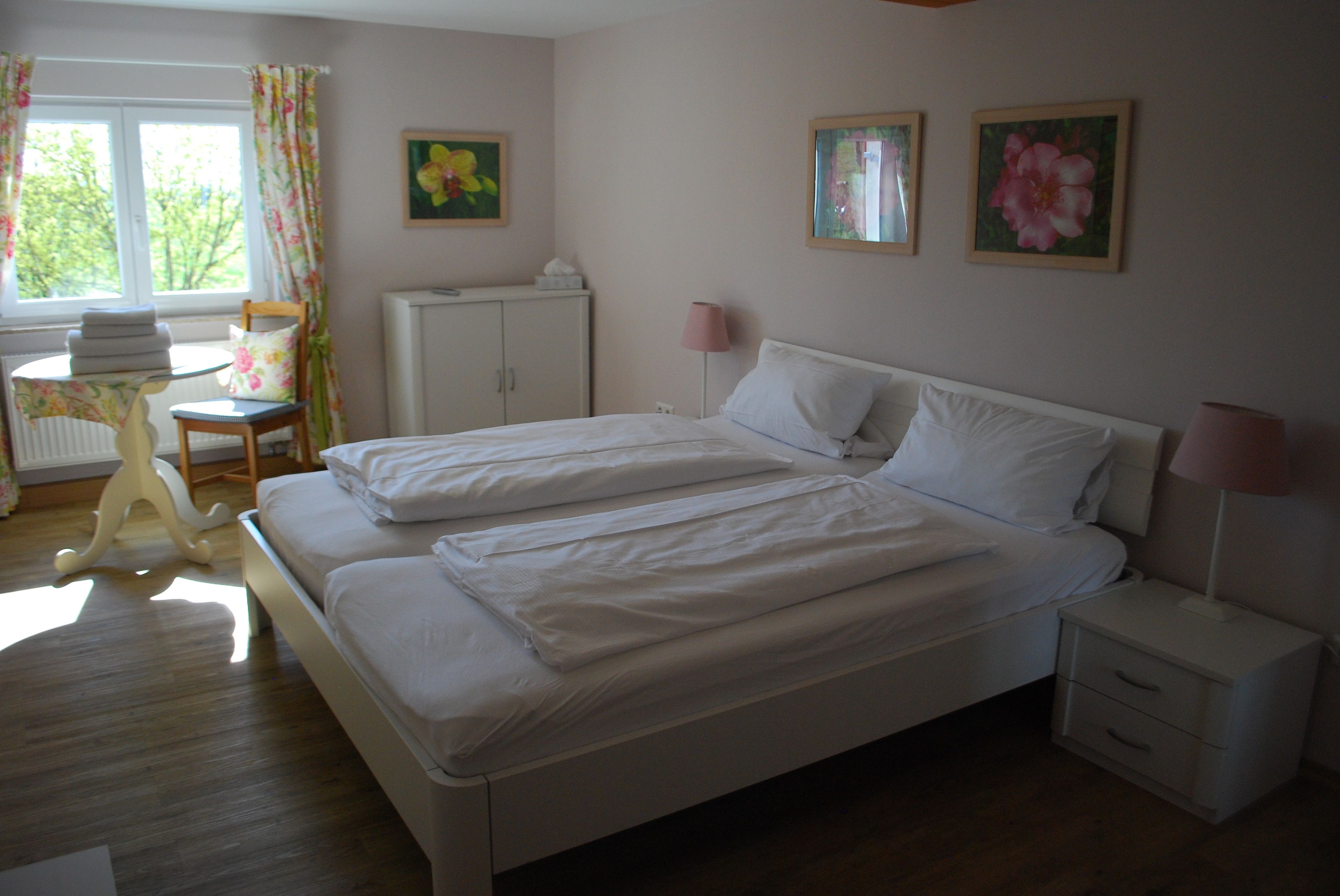 Un dormitorio con dos camas, un escritorio con silla, un armario y dos lámparas fijadas a la pared.