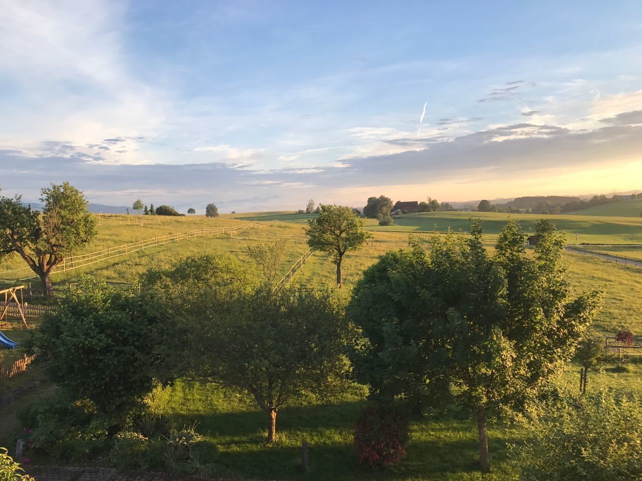 Un paysage rural avec de vastes champs, des arbres et une clôture en bois.