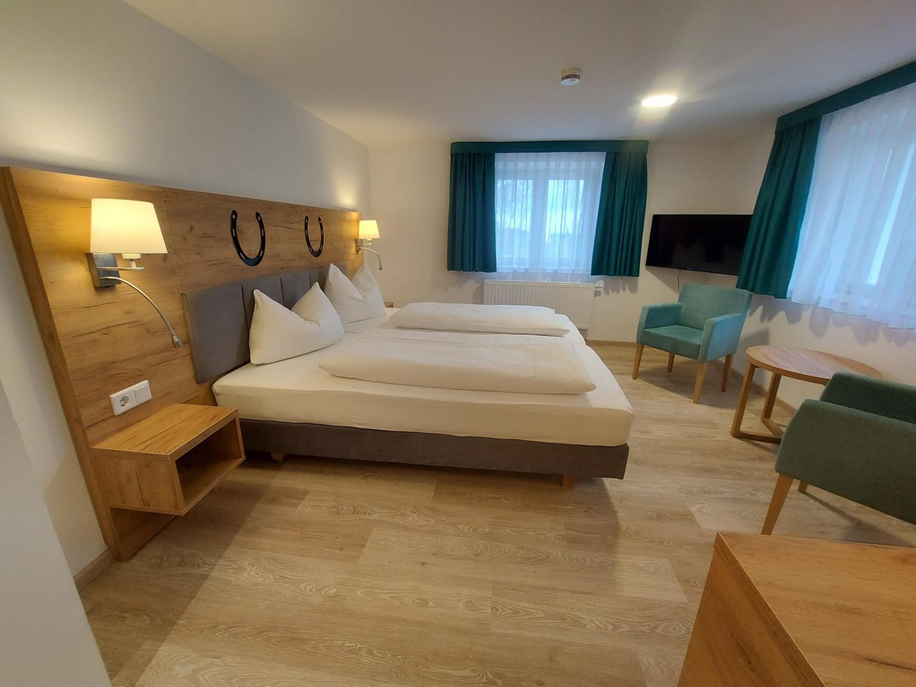A hotel room with a large bed, two bedside tables, a desk, a chair, and a TV.