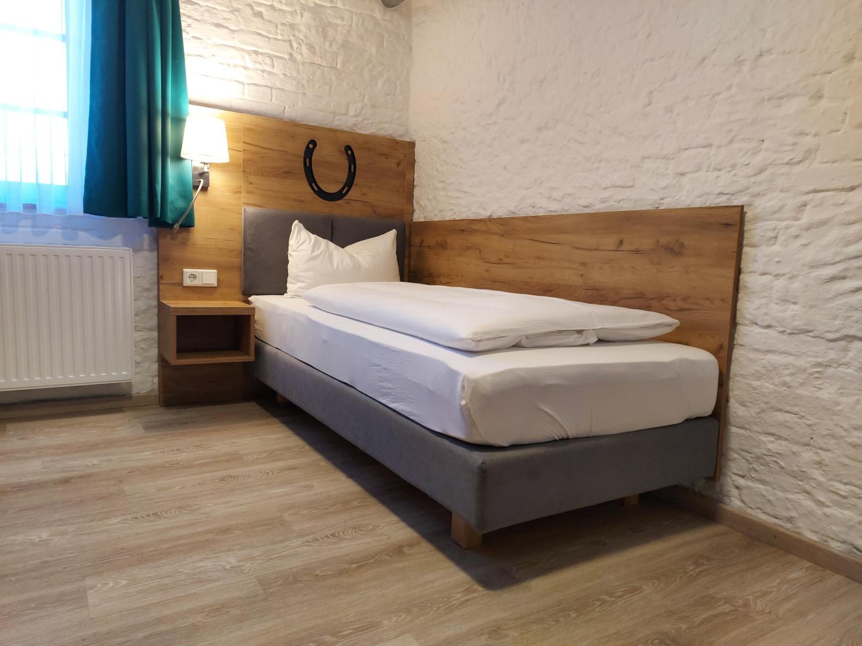 Ein ordentlich eingerichtetes Schlafzimmer mit einem hölzernen Kopfteil, einem Nachttisch und einer Heizung.