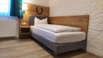 Ein ordentlich eingerichtetes Schlafzimmer mit einem hölzernen Kopfteil, einem Nachttisch und einer Heizung.