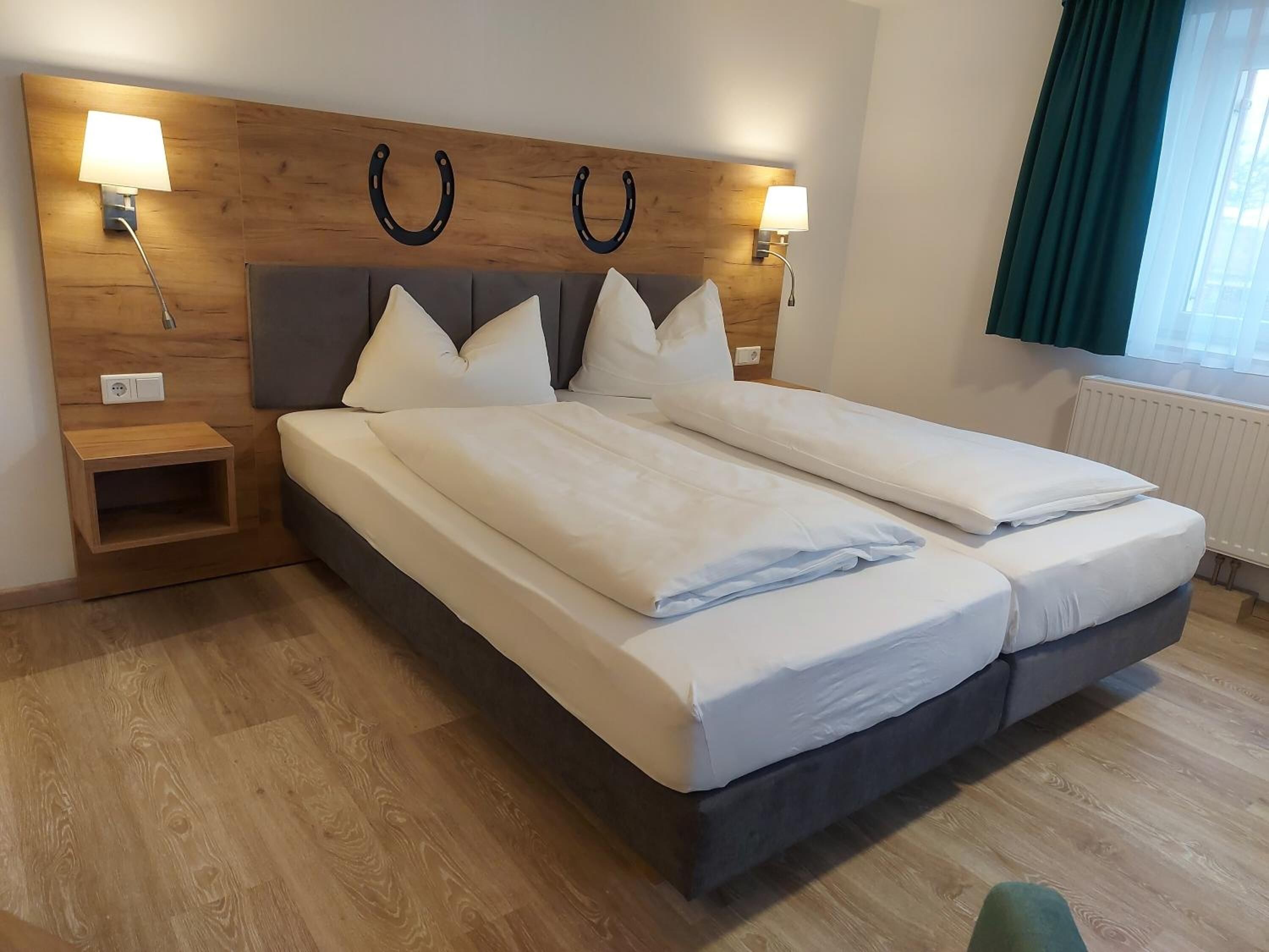 Un lit double avec une tête de lit en bois, deux tables de chevet et une petite table de nuit.