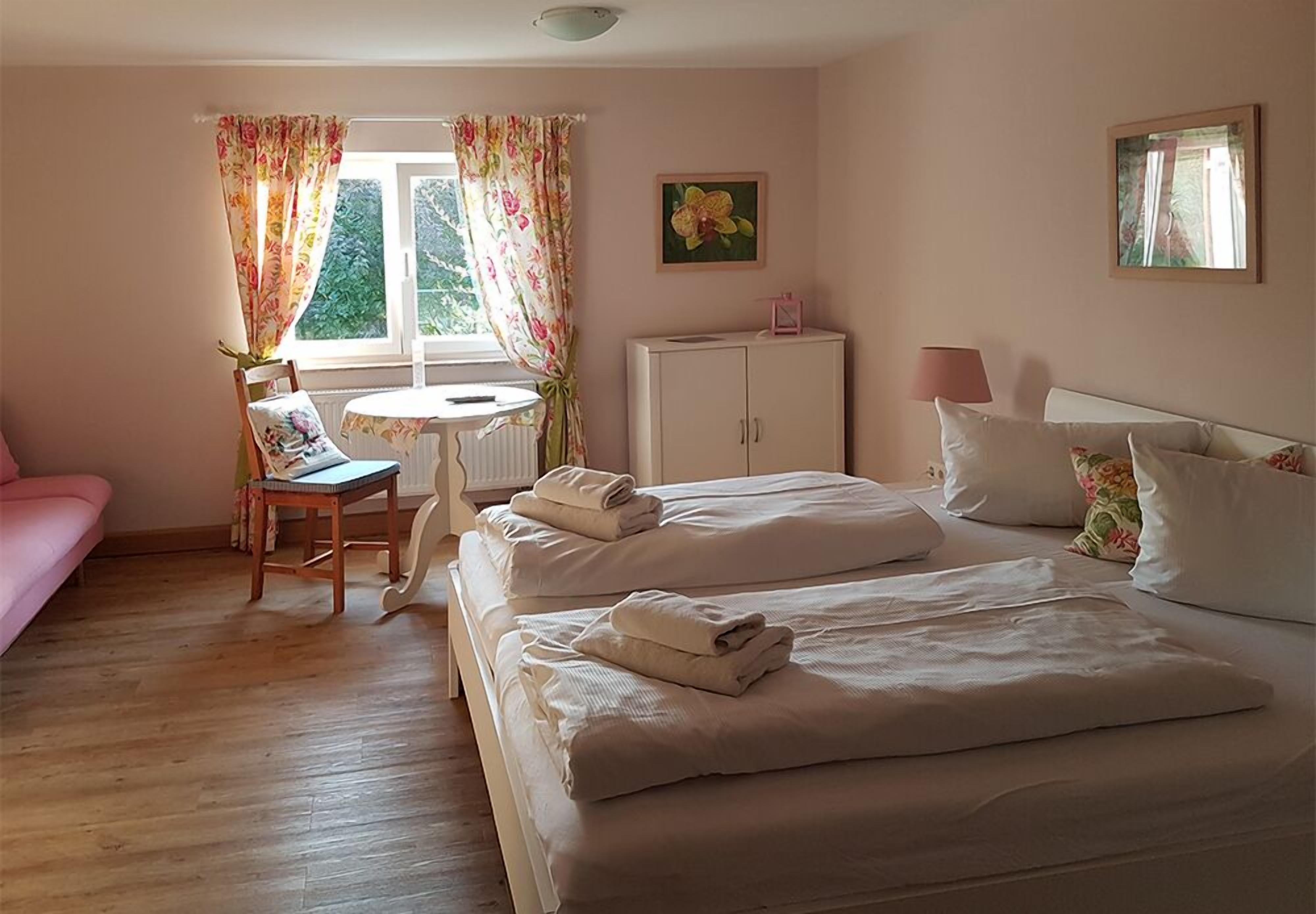 A bedroom with two beds, a desk, a chair, a cabinet, and a window with curtains.