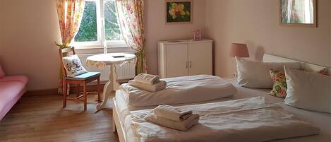 A bedroom with two beds, a desk, a chair, a cabinet, and a window with curtains.