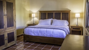 Une chambre à coucher avec un lit en bois, deux tables de chevet avec des lampes et une armoire.
