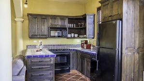 Une cuisine de taille réduite, avec des meubles de rangement en bois foncé, un réfrigérateur noir et un pare-feu en carrelage.