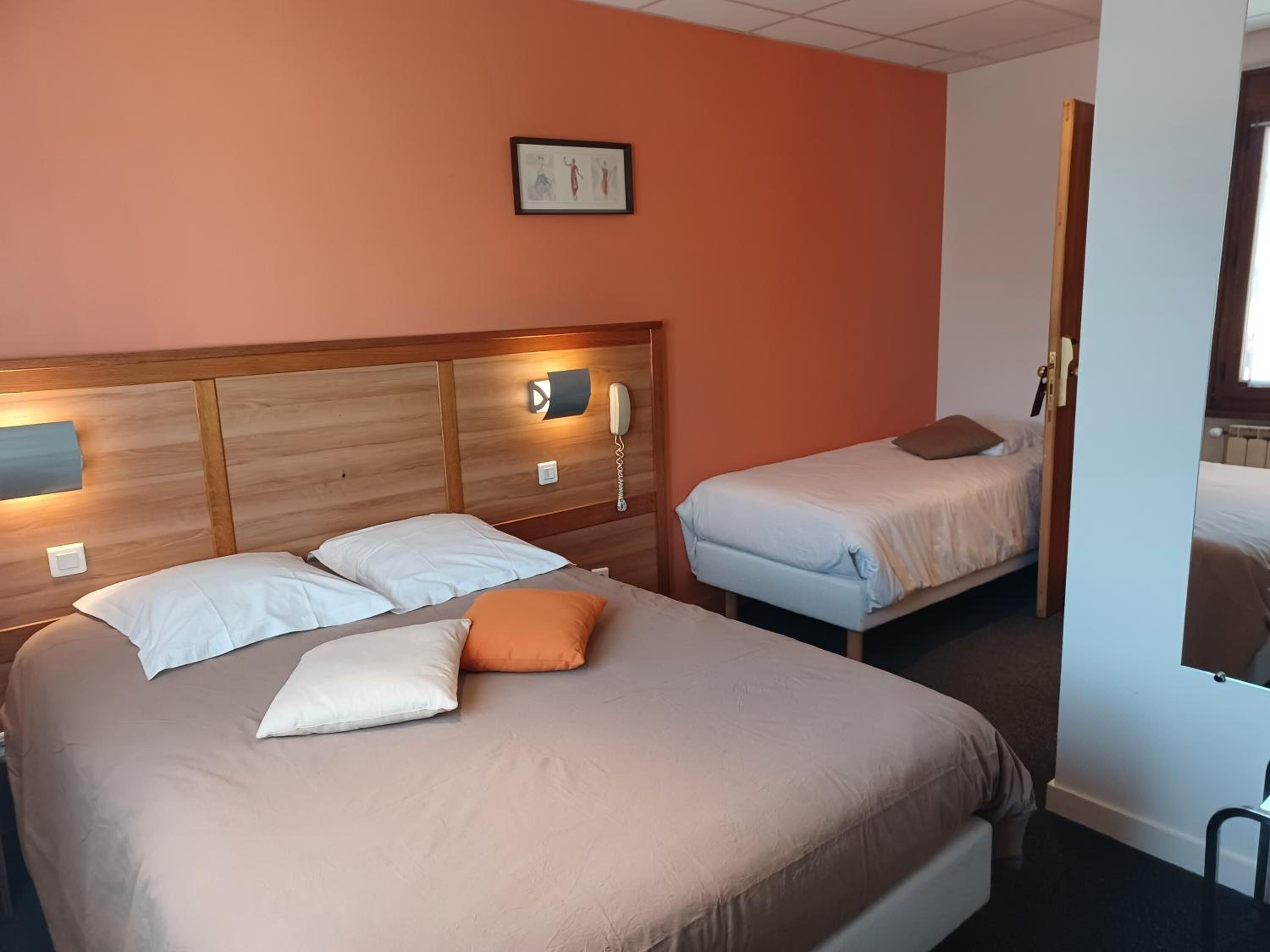 A hotel room with two beds, a wooden headboard, a bedside lamp, and a framed picture on the wall.