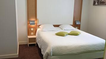 A hotel room with a bed, bedside tables, a lamp, and a wall-mounted picture.