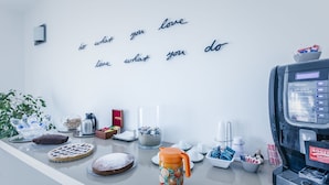 A kitchen counter with a coffee machine, a bowl of cookies, a pie, and a motivational quote on the wall. - B&B La Postale (San Salvo)