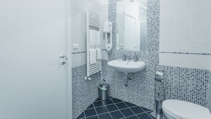 A bathroom with a white sink, mirror, and toilet, tiled with small blue and white tiles. - B&B La Postale (San Salvo)