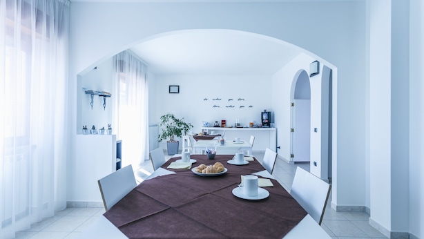 A modern dining area with a long table, chairs, and a coffee machine. - B&B La Postale (San Salvo)