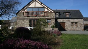 Une maison en pierre avec un balcon, une porte en bois et une petite fenêtre.