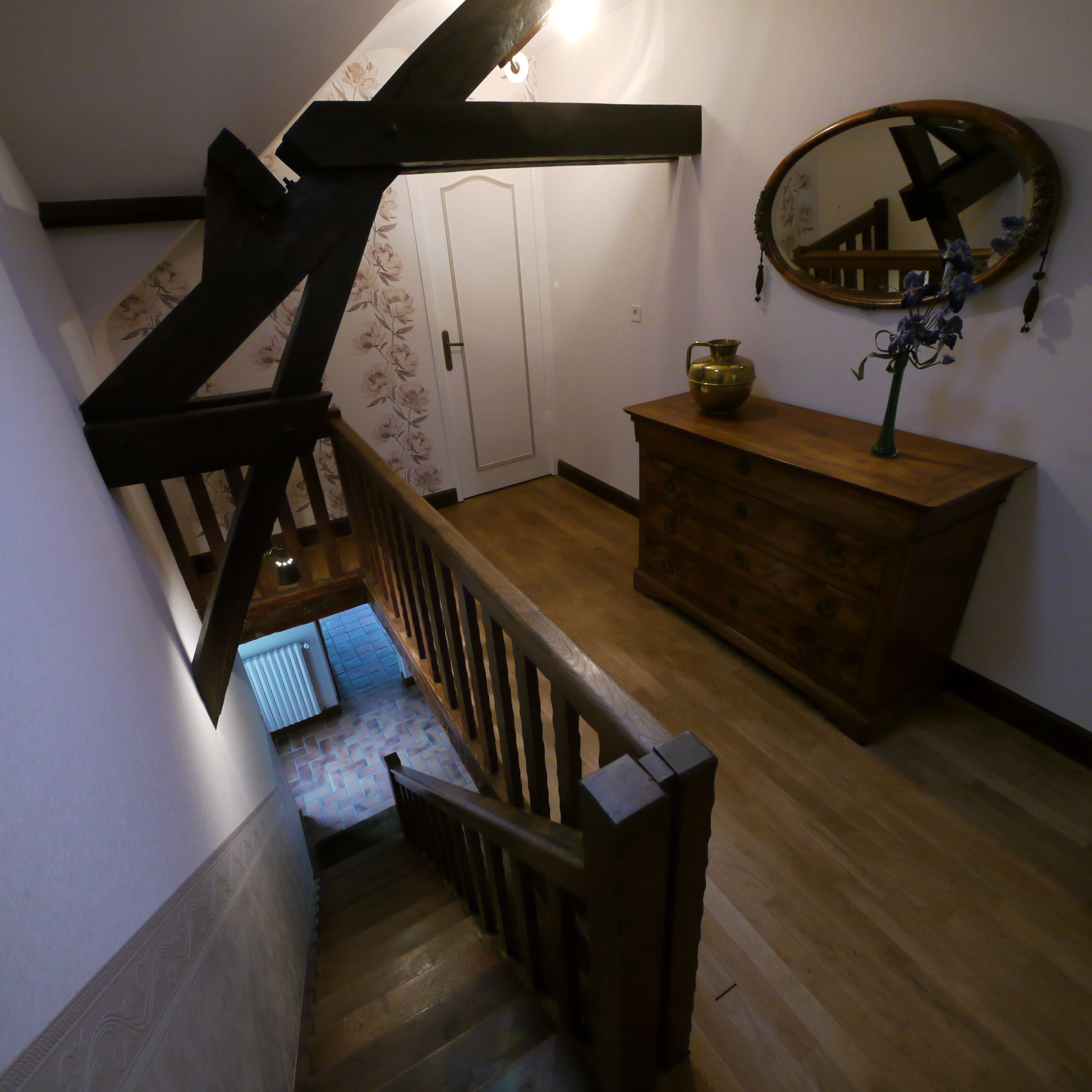 A wooden staircase with a handrail, a wooden dresser, and a mirror on the wall.