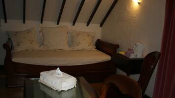 A bedroom with a bed, a bedside table with a lamp, a chair, and a glass table with a tissue box.