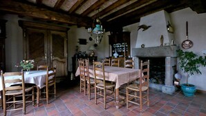 Un coin repas avec une table et des chaises en bois, un lustre et une cheminée.
