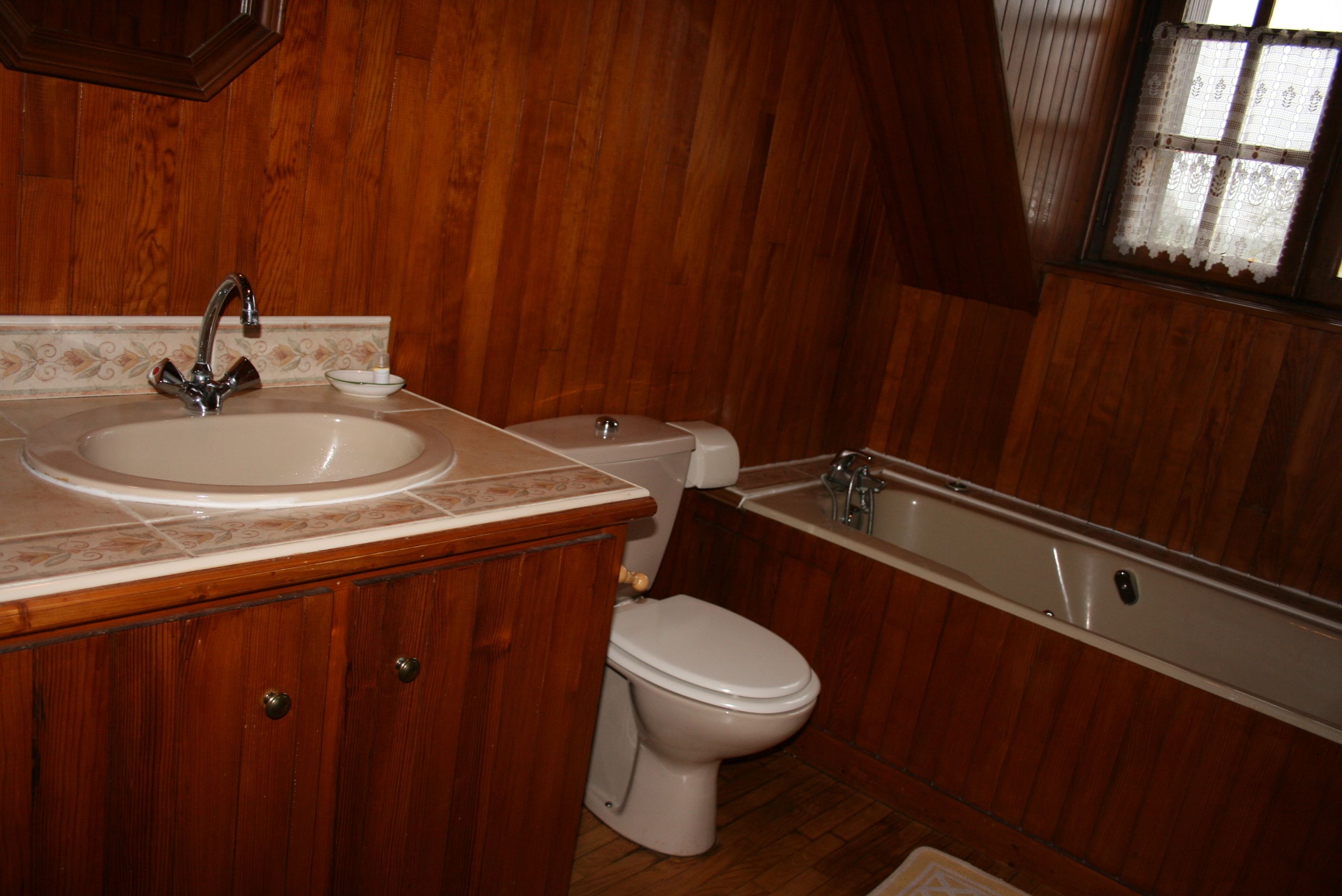 A wooden-paneled bathroom with a sink, toilet, and bathtub.