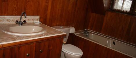 A wooden-paneled bathroom with a sink, toilet, and bathtub.