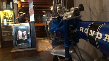A motorcycle with a blue and silver color scheme, a visible "HONDA" logo, and a bar area with stools and a refrigerator in the background.